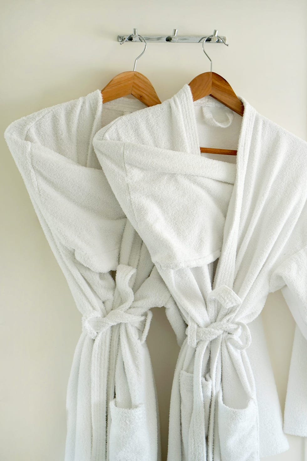 two white coats hanging on the door. hotel dressing gowns on the door hanger.