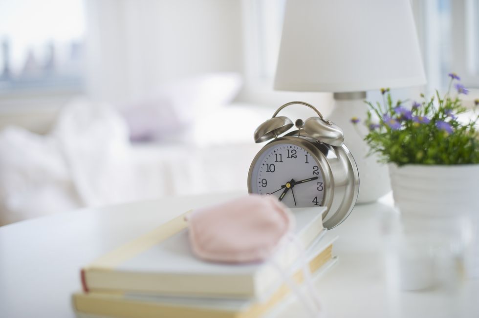 Sleep mask books and alarm clock on bedside table