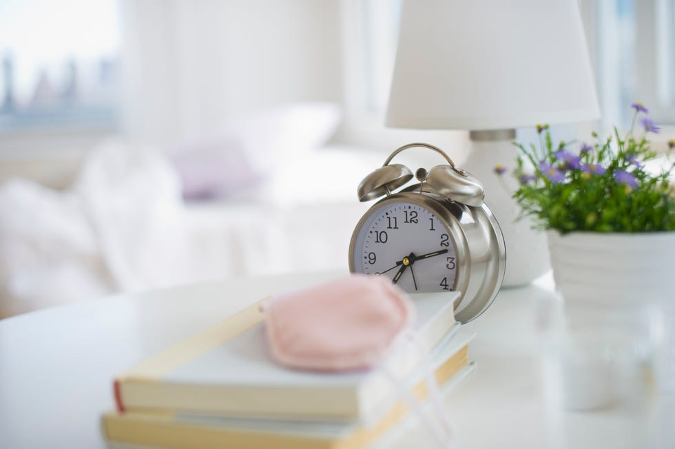 Sleep mask books and alarm clock on bedside table