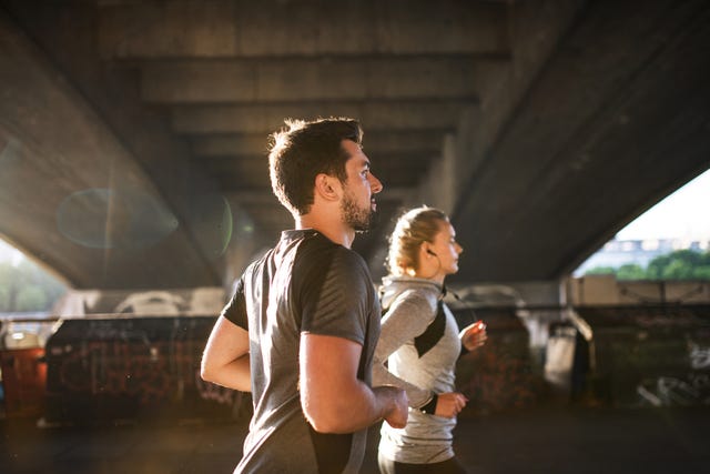 an attractive male and female runners jogging in london, listening to music