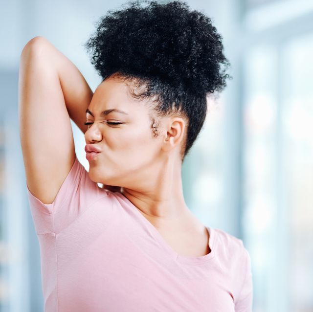 shot of an attractive young woman smelling her armpits during her morning routine