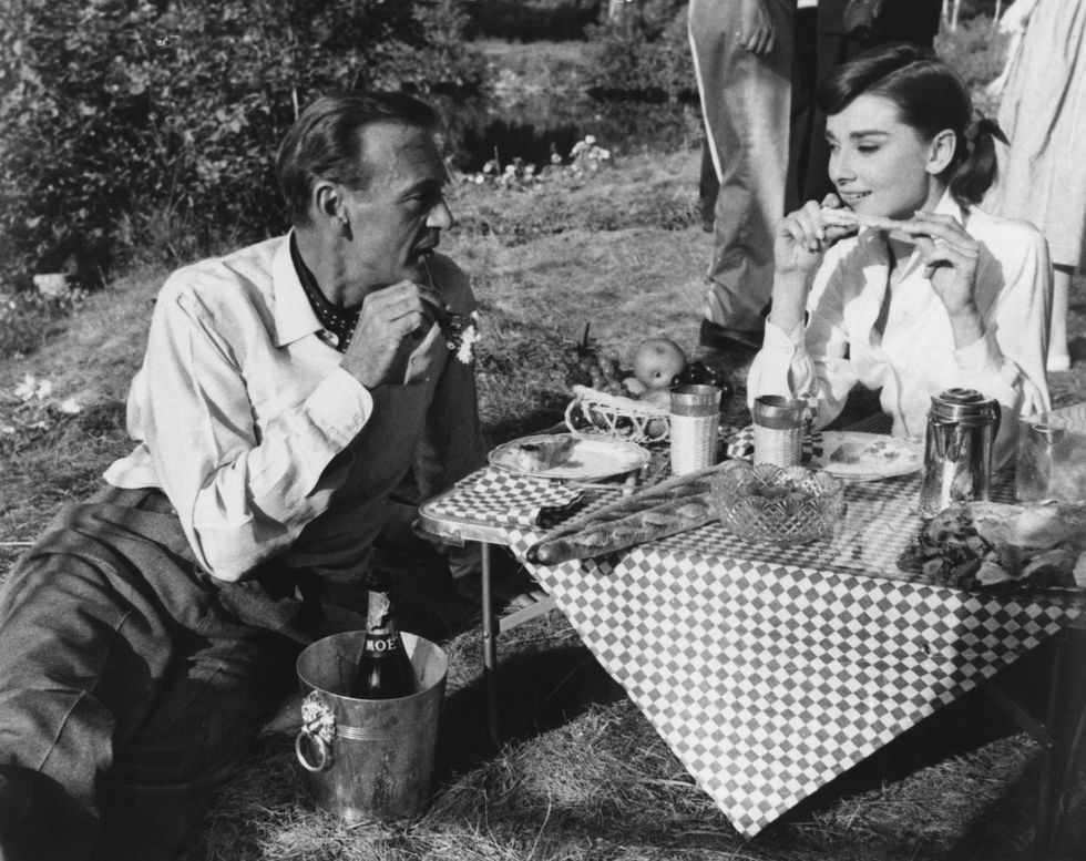 Gary Cooper and Audrey Hepburn share a picnic on the set of the film Love in the Afternoon.