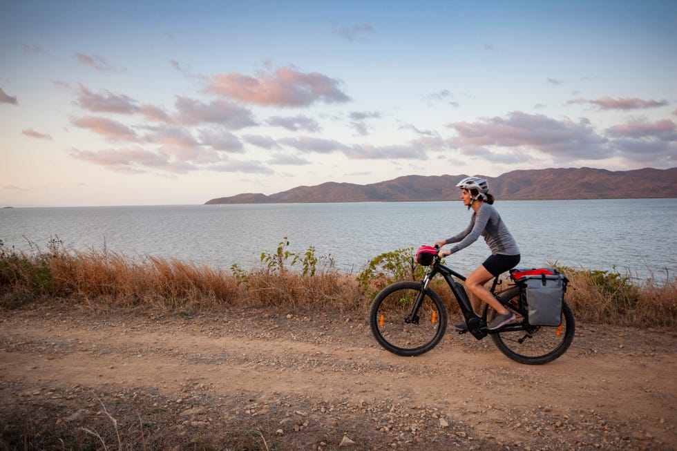 woman riding an e bike on an unsealed road, cape pallarenda, far north queensland, australia