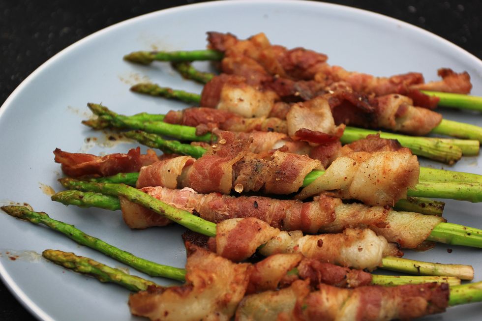 grilled bacon wrapped green asparagus on dark background