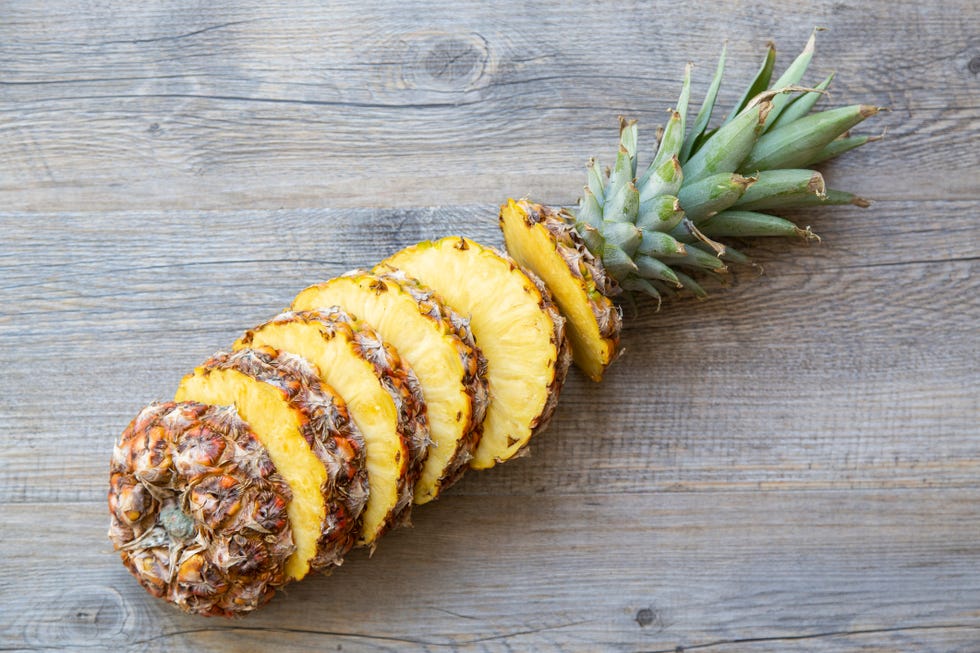 whole sliced pineapple on a wood background