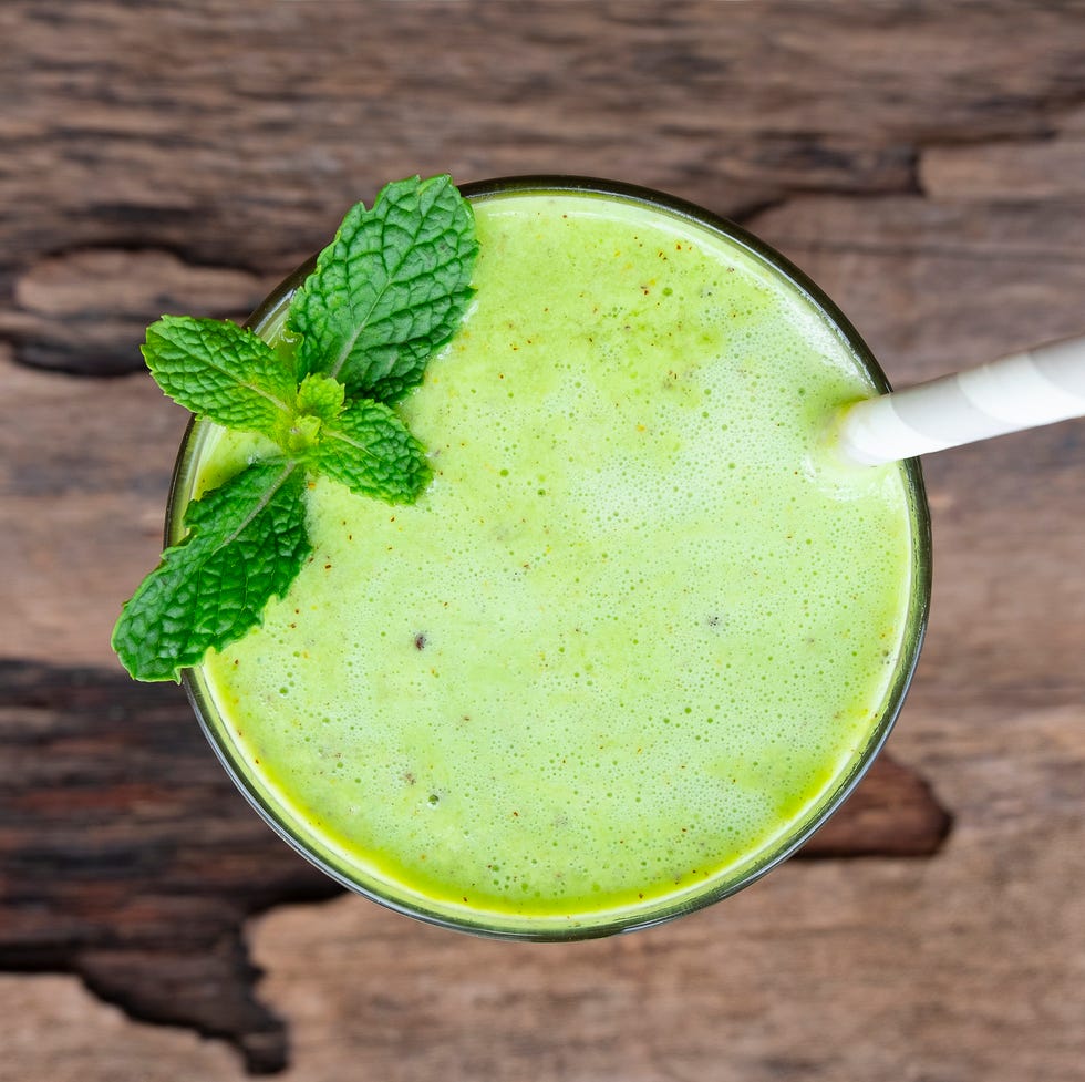 Kiwi yogurt fruit juice smoothie and green kiwi juice drink healthy, delicious taste in a glass for weight loss on a white wooden background from the top view.