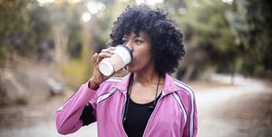 a young black woman walking with a cup of coffee