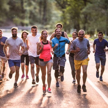 Full length of marathon runners having a race through nature. large group of athletic people running a marathon on the road