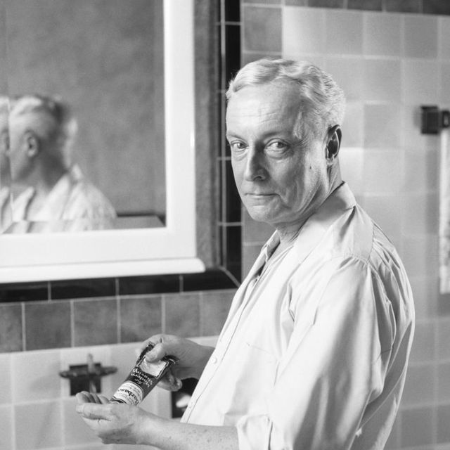 1920s senior man standing in shirt sleeves at bathroom sink looking at camera squeezing grooming product from tube into hand photo by h armstrong robertsclassicstockgetty images