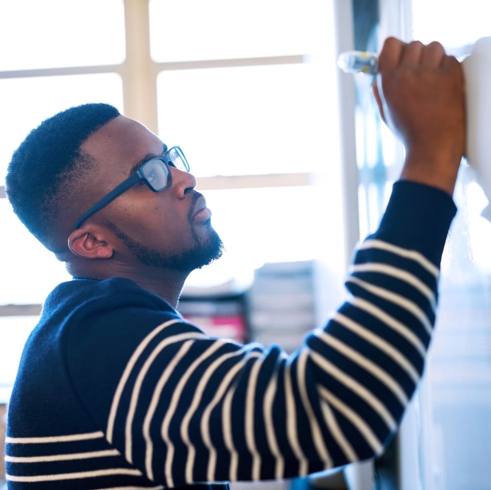 cropped shot of a young man writing on a whiteboard in a classroom