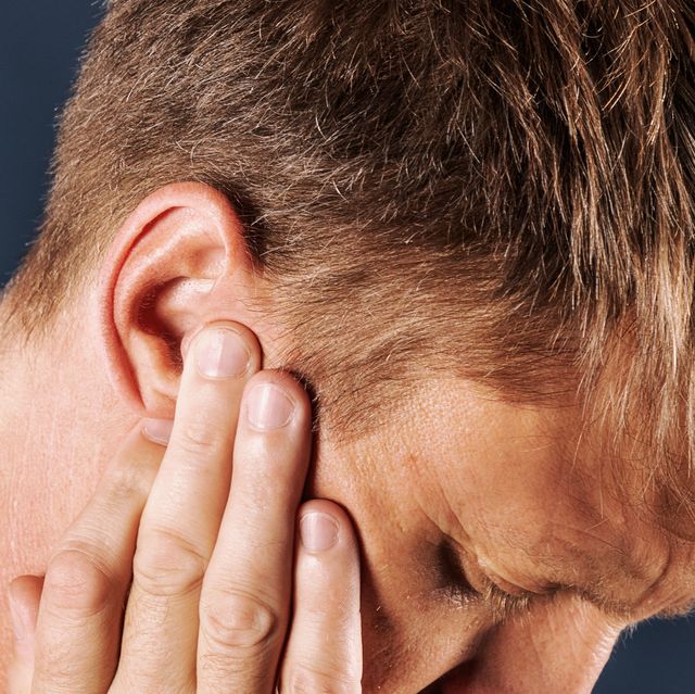 man with fingers at ears looking like he's in pain