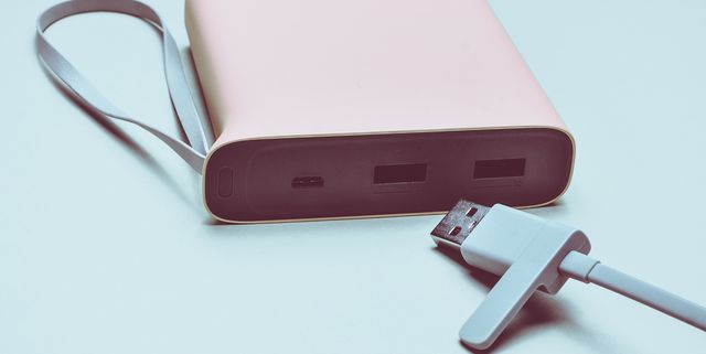 Power bank for charging smartphones and gadgets with a usb cable close-up on a green background. Modern technologies.