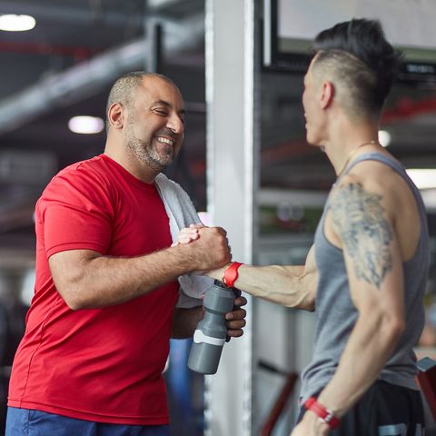Smiling man greeting fitness instructor at gym