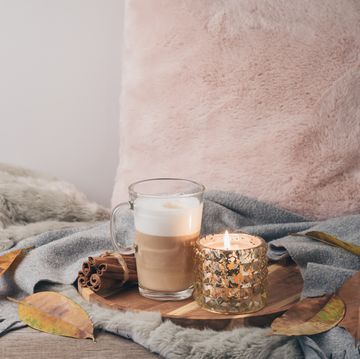 Hygge Scandinavian style concept with latte macchiato coffee cup, candles and book