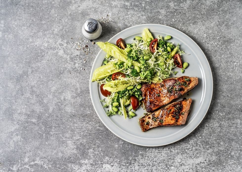 a plate of pan seared salmon with fresh salad on gray background