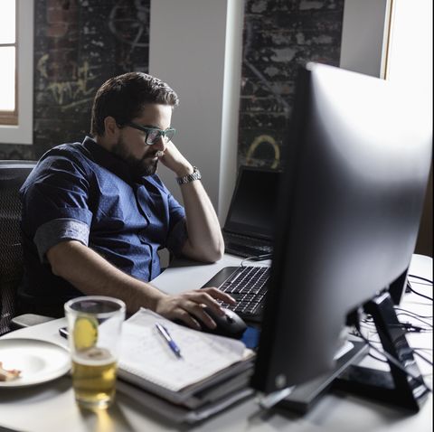 Creative businessman working and eating pizza and drinking beer at desk