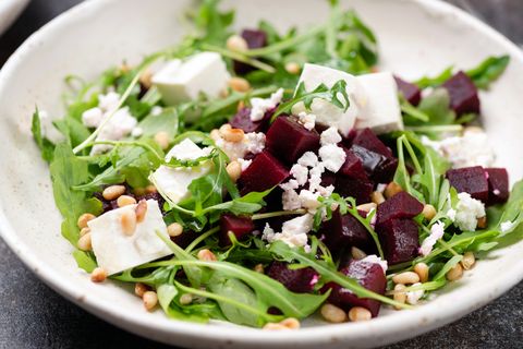 roasted beet and feta salad with arugula and pine nuts in bowl closeup view