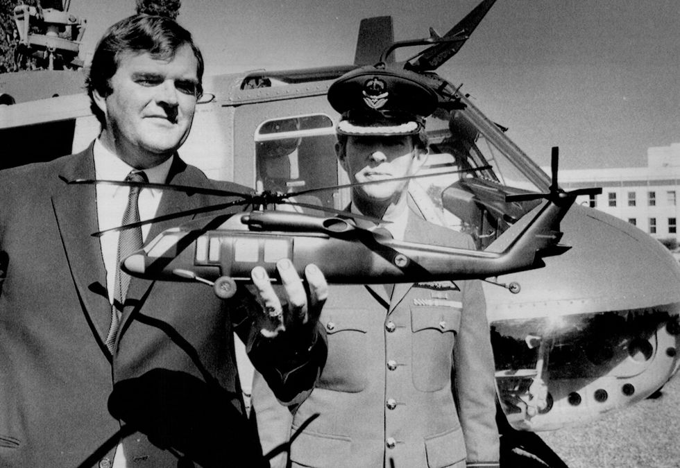 mr kim beazley and group captain terry wilson, who is the project manager for the sikorsky helicopter, which will replace out iriquois, mr beazley holds a model of a sikorsky s70 a 9 black hawk for the raaf which was delivered by the iriquois helicopter in the background may 1, 1986 photo by david james barthofairfax media via getty images