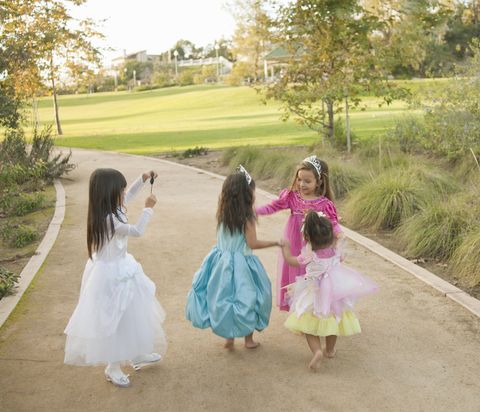 girls in princess dresses dancing together at park