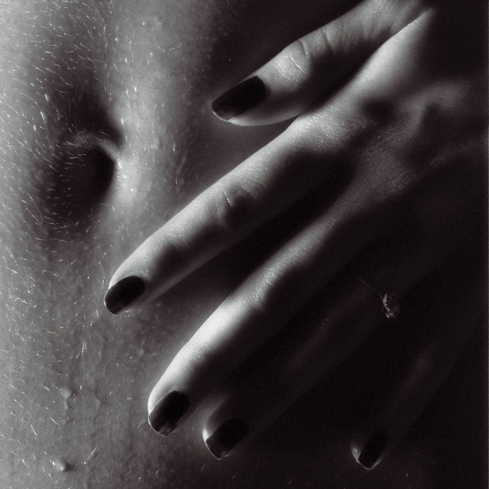 close up image of womans belly with hand lying near a belly button