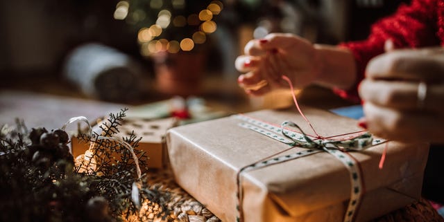 young woman wrapping christmas gifts in living room