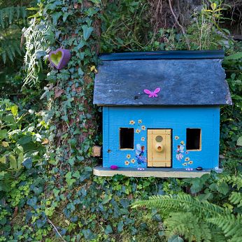 blue fairy house along the path on the coast of ireland house is blue with yellow door, in a green lush forest