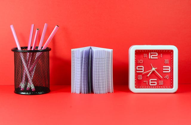 stationery items including a clock notepad and pens on a red background