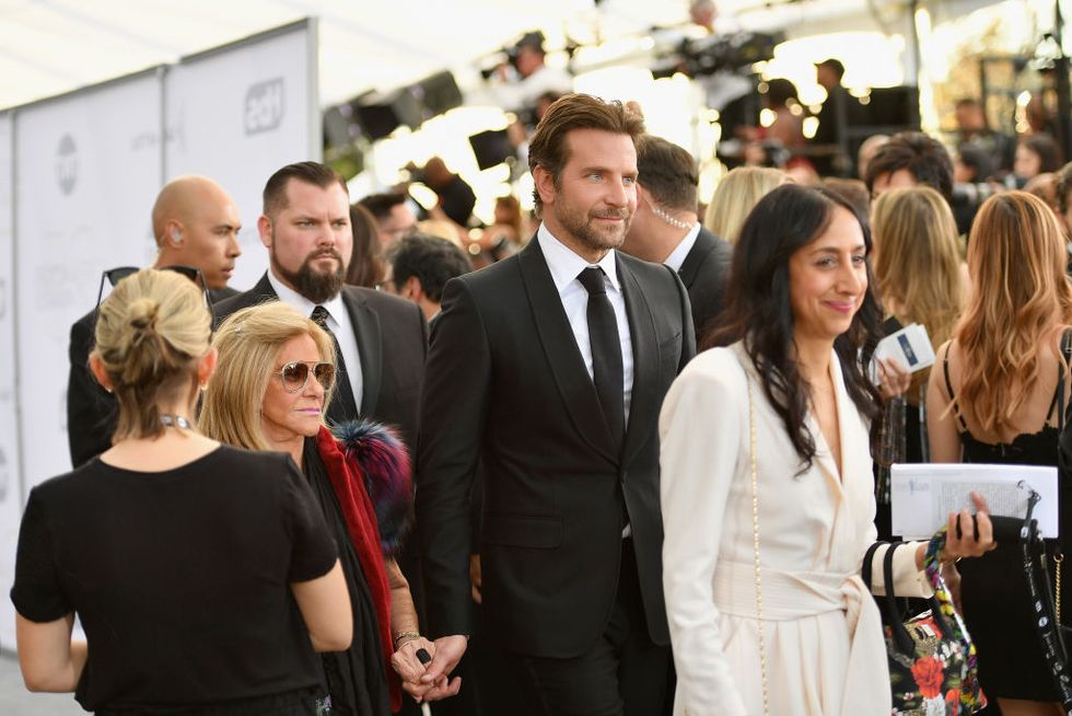 Bradley Cooper leading his mother by the hand on the red carpet