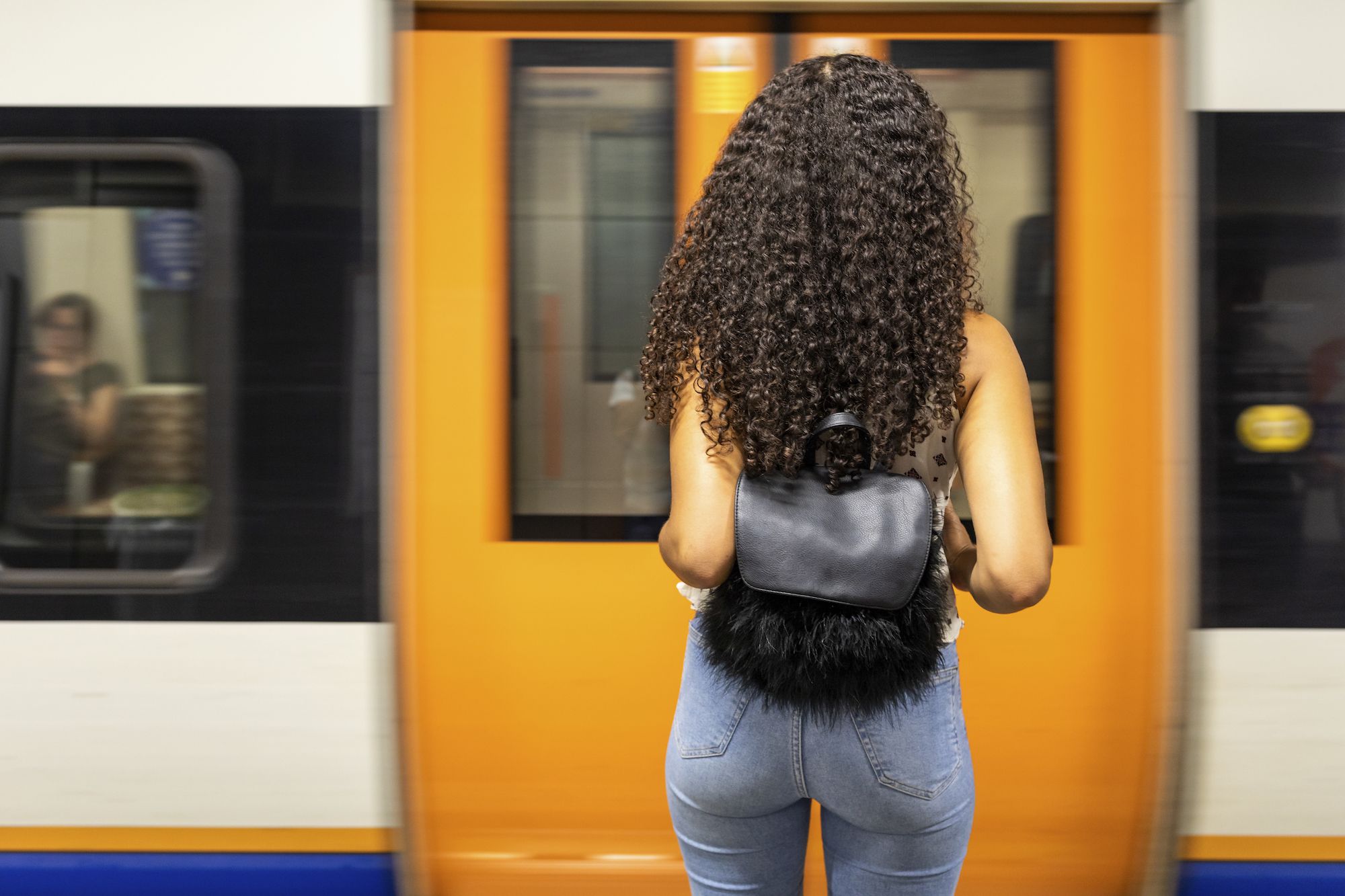 UK, London,  rear view of young woman waiting at underground station platform