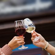 Two people clinking glasses with red and white wine