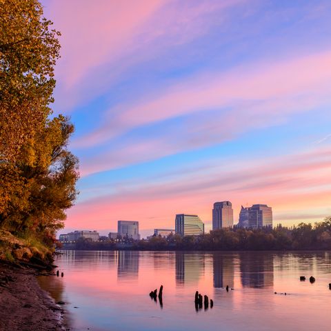 the sacramento skyline is reflected in the sacramento river at sunrise during the fall