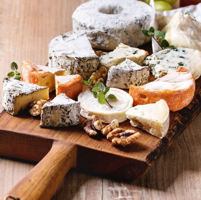 cheese plate assortment of french cheese served with honey, walnuts, bread and grapes on rustic wooden serving board over wood texture background close up photo by natasha breenredacouniversal images group via getty images