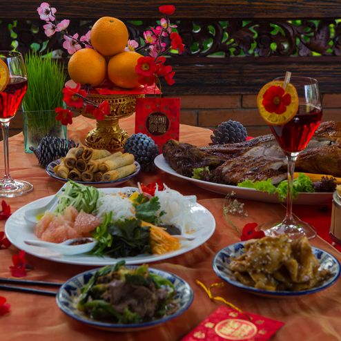 chinese new year party table in red and gold theme with food, drinks and decorations