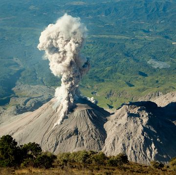the active lava dome of santiaguito volcano with an eruption sending ash into the air seen from the summit of santa maria volcano, guatemala