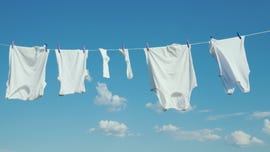 snow white white linen dries on a rope against a blue sky background.