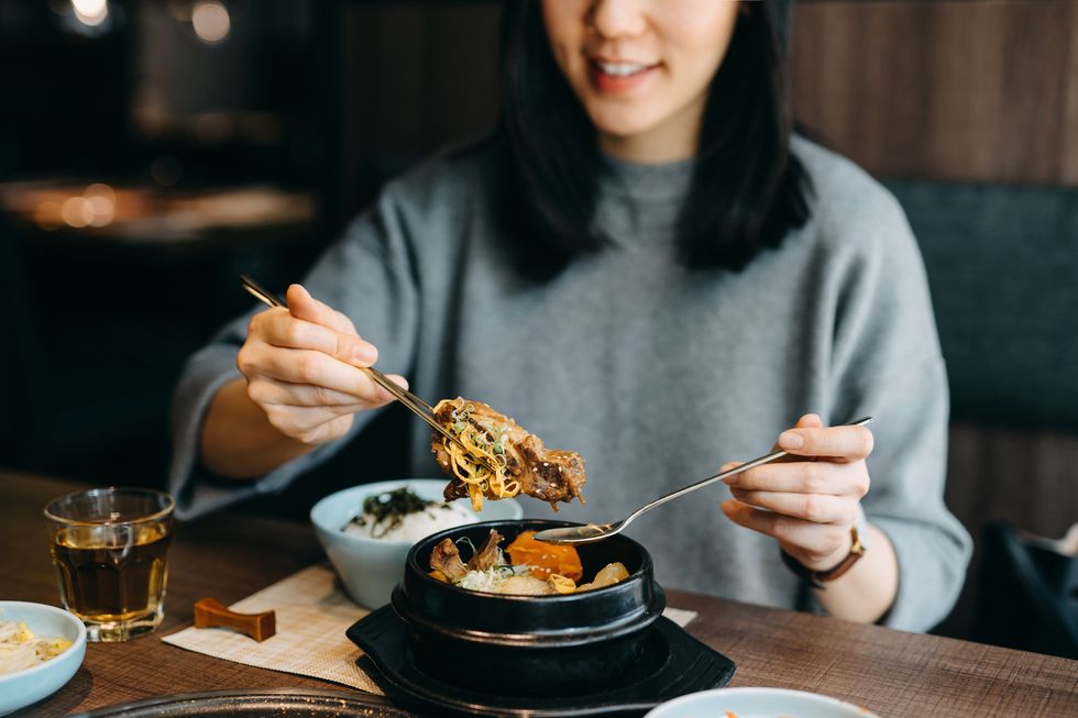 smiling young asian woman enjoying korean meal in a korean restaurant
