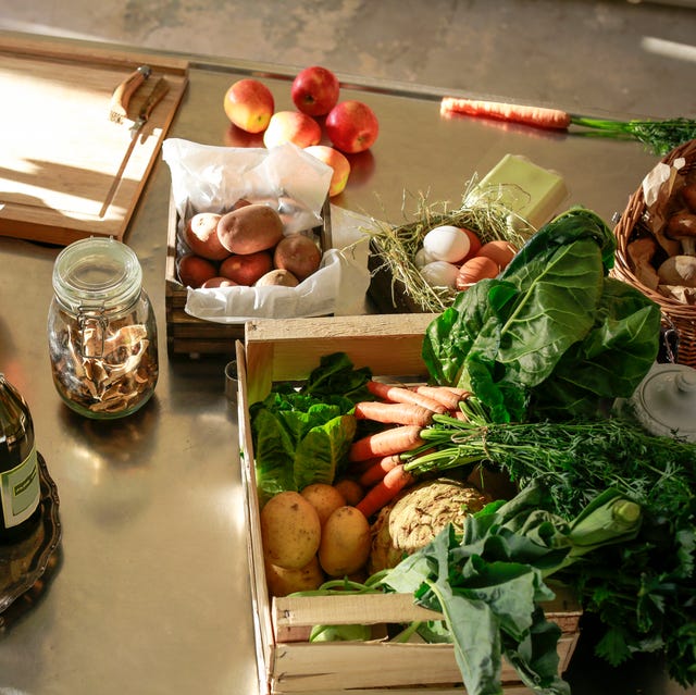 Fresh orgnaic vegetables and fruits in a kitchen a table is filled with food