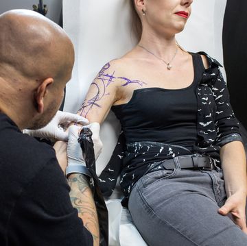 vrouw laat tatoeage op haar bovenarm zetten