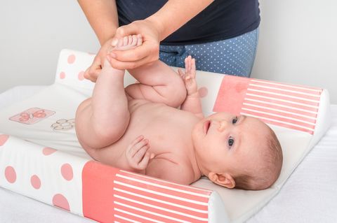 mother is changing diaper to her little baby in child room at home