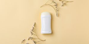 White deodorant and herbs on color background