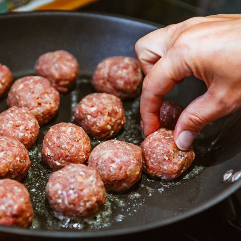 Cropped Image Of Hand Frying Meatballs In Pan