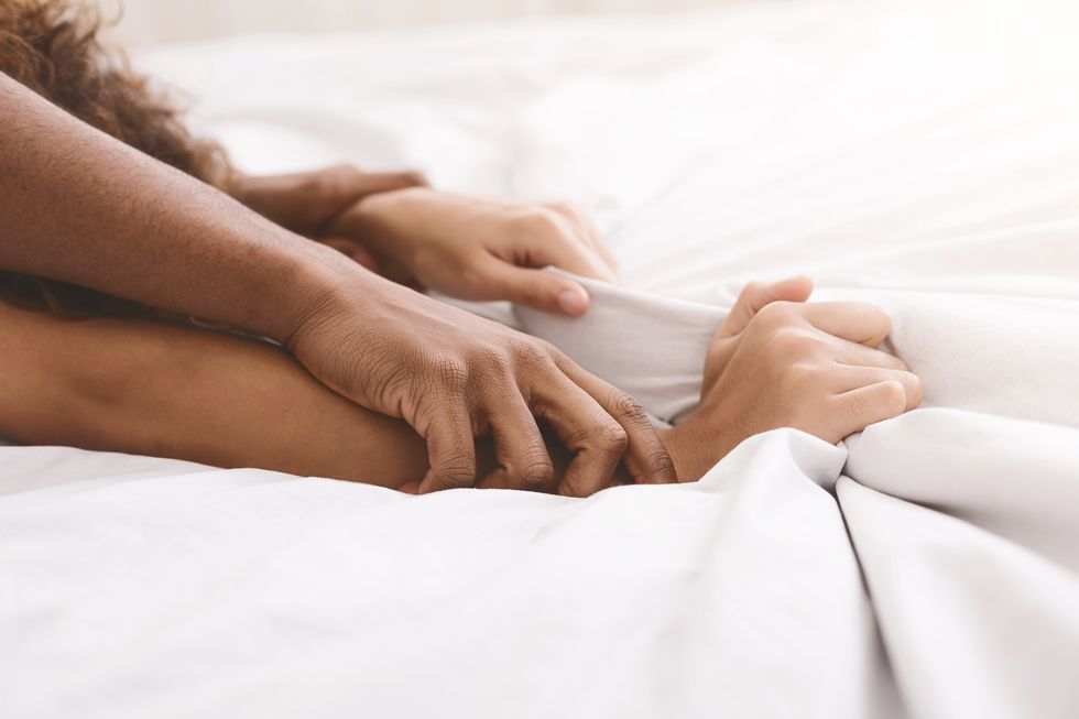 passion in bed african american couple hands pulling white sheets in ecstasy, closeup
