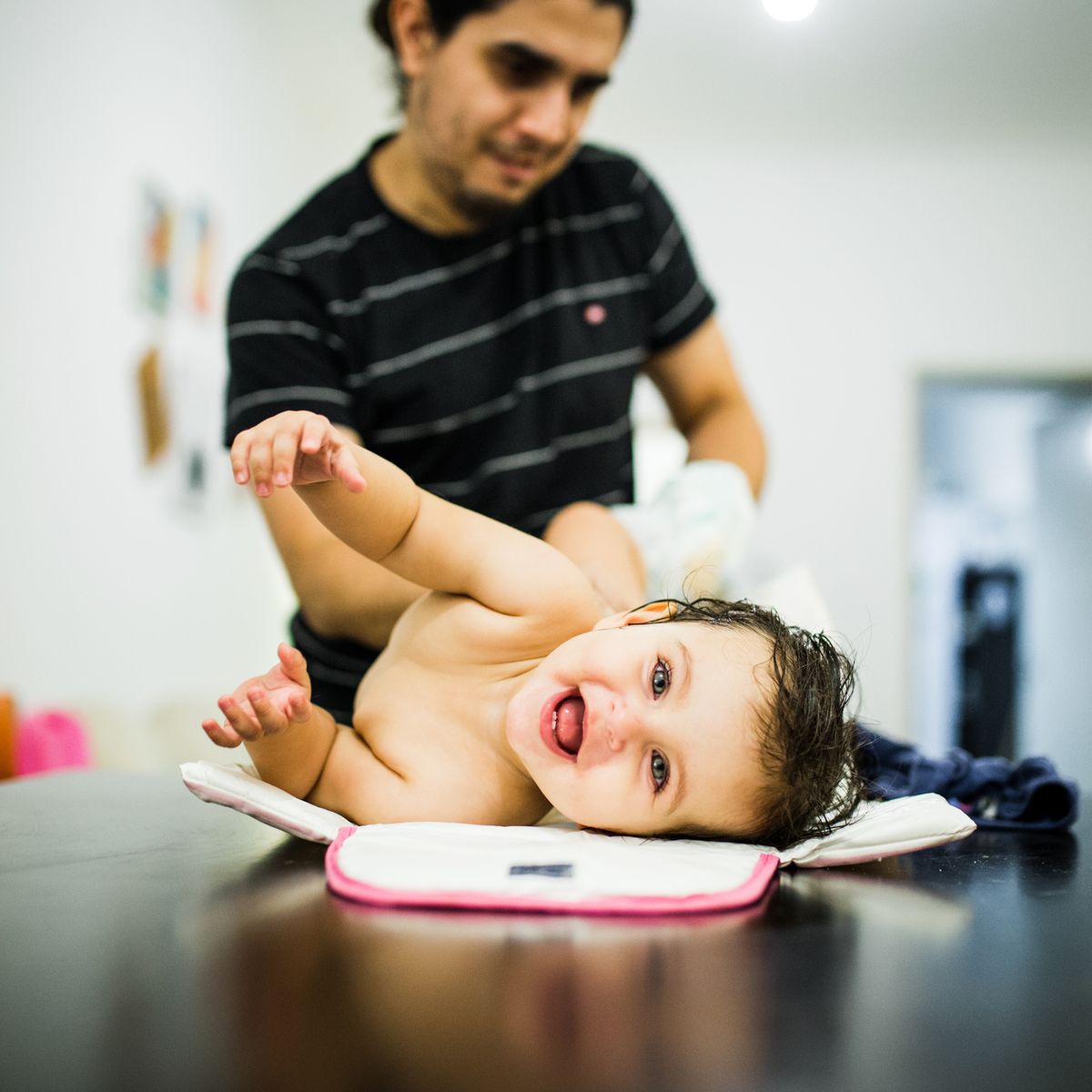 Midsection Of Father With Smiling Baby On Table