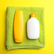 green terry towel and sunscreen on bright yellow background concept hygiene, body care top view, copy psace