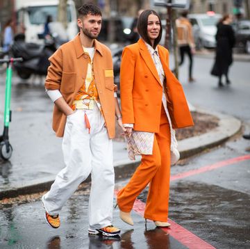 een man en een vrouw lopen in oranje kleding op straat