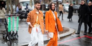 een man en een vrouw lopen in oranje kleding op straat