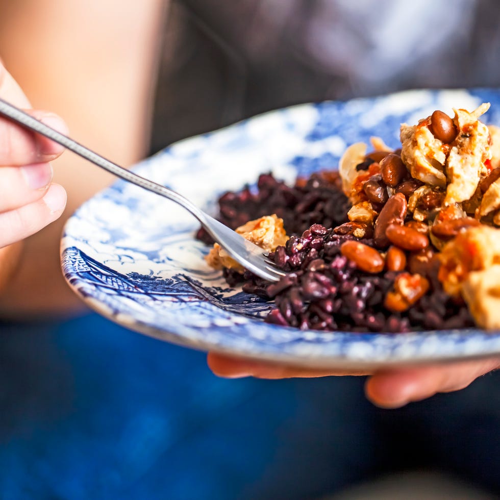 Man eating homemade dinner. chicken meat with pinto beans and black rice