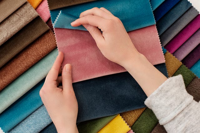 young woman with fabric samples for curtains at table. multiple color fabric texture samples selection fabrics for interior decoration. furniture upholstery