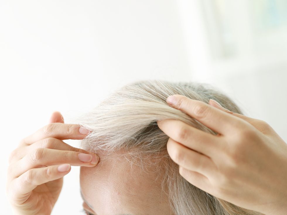 older woman checking her hair for hair loss