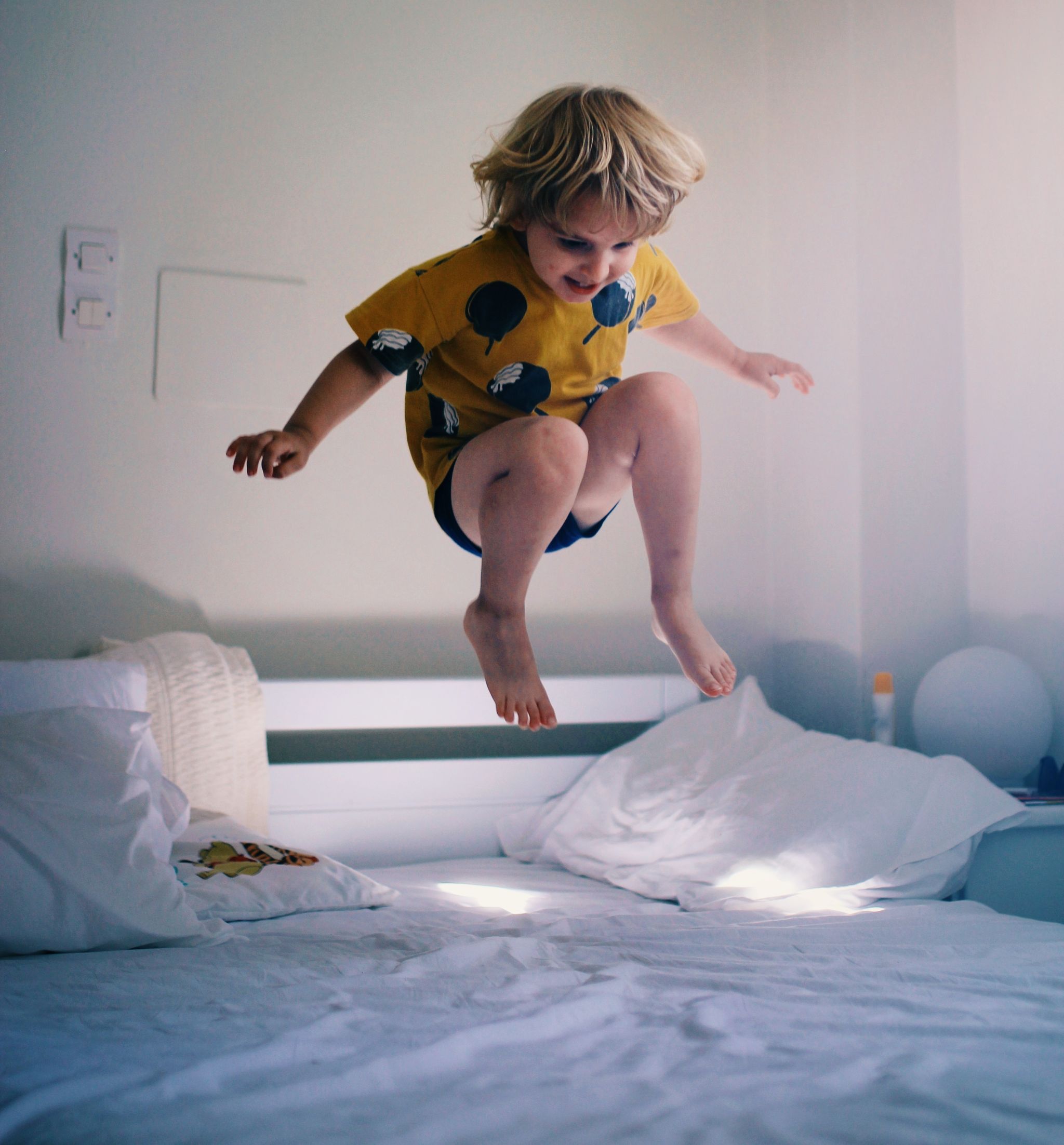 Full Length Of Boy Jumping On Bed At Home